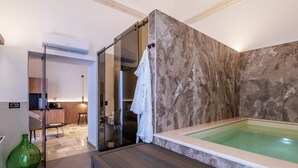 A modern bathroom with a marble wall, a bathtub, and a glass shower enclosure. - buone maniere exclusive room (Martina Franca)