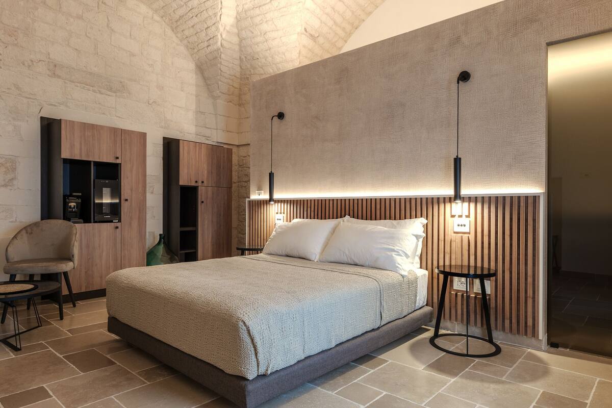 Une chambre à coucher moderne avec un grand lit, une armoire en bois, une petite table et une chaise.