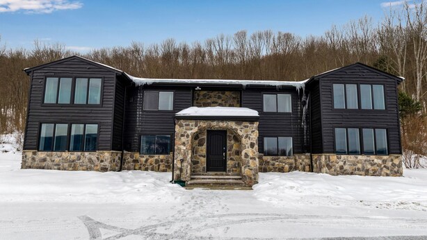A two-story house with a stone entrance and a snow-covered roof.