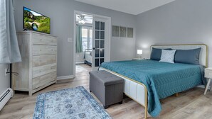 A bedroom with a bed, a dresser, a television, and a view of a bathroom. - Ellicottville 2 miles to Holiday Valley Condo 4 (Great Valley)