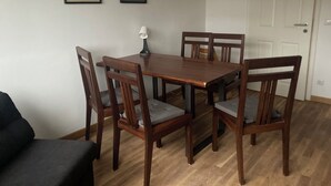 Un comedor con una mesa de madera y cuatro sillas, una lámpara sobre la mesa e impresiones botánicas enmarcadas en la pared.