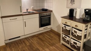 Una cocina con armarios blancos, horno doble, pileta y cafetera.