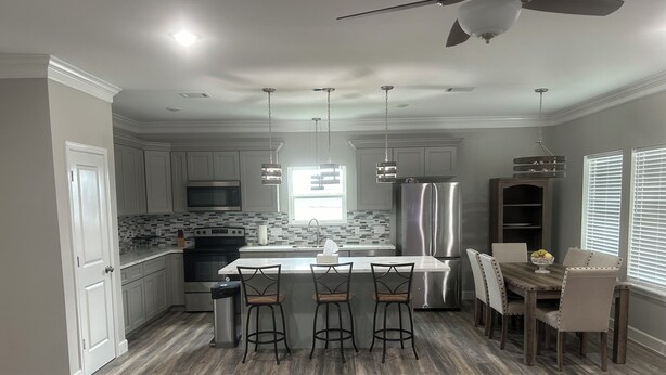 A modern kitchen with a central island, stainless steel appliances, and a dining area with bar stools.