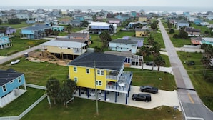 A residential area with houses, a yellow building with a balcony, and a road.