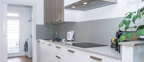 Una cocina moderna con gabinetes blancos, encimera negra y estufa integrada.