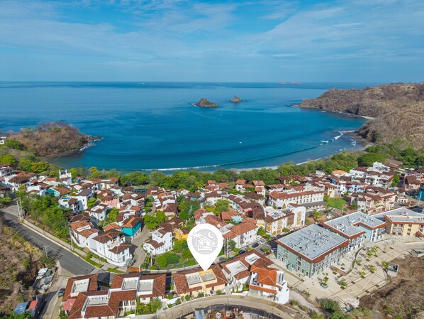 An aerial view of a coastal town with buildings, roads, and the sea. - Sunset Oceanview Villa w/ Private Plunge Pool (Las Catalinas)