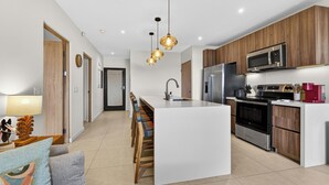 A modern kitchen with a central island, wooden cabinets, stainless steel appliances, and pendant lighting.