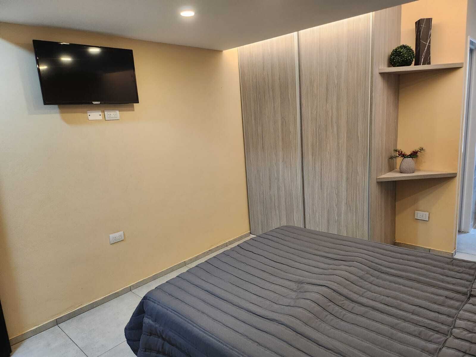 Quarto com cama, televisão de tela plana na parede e armários embutidos.