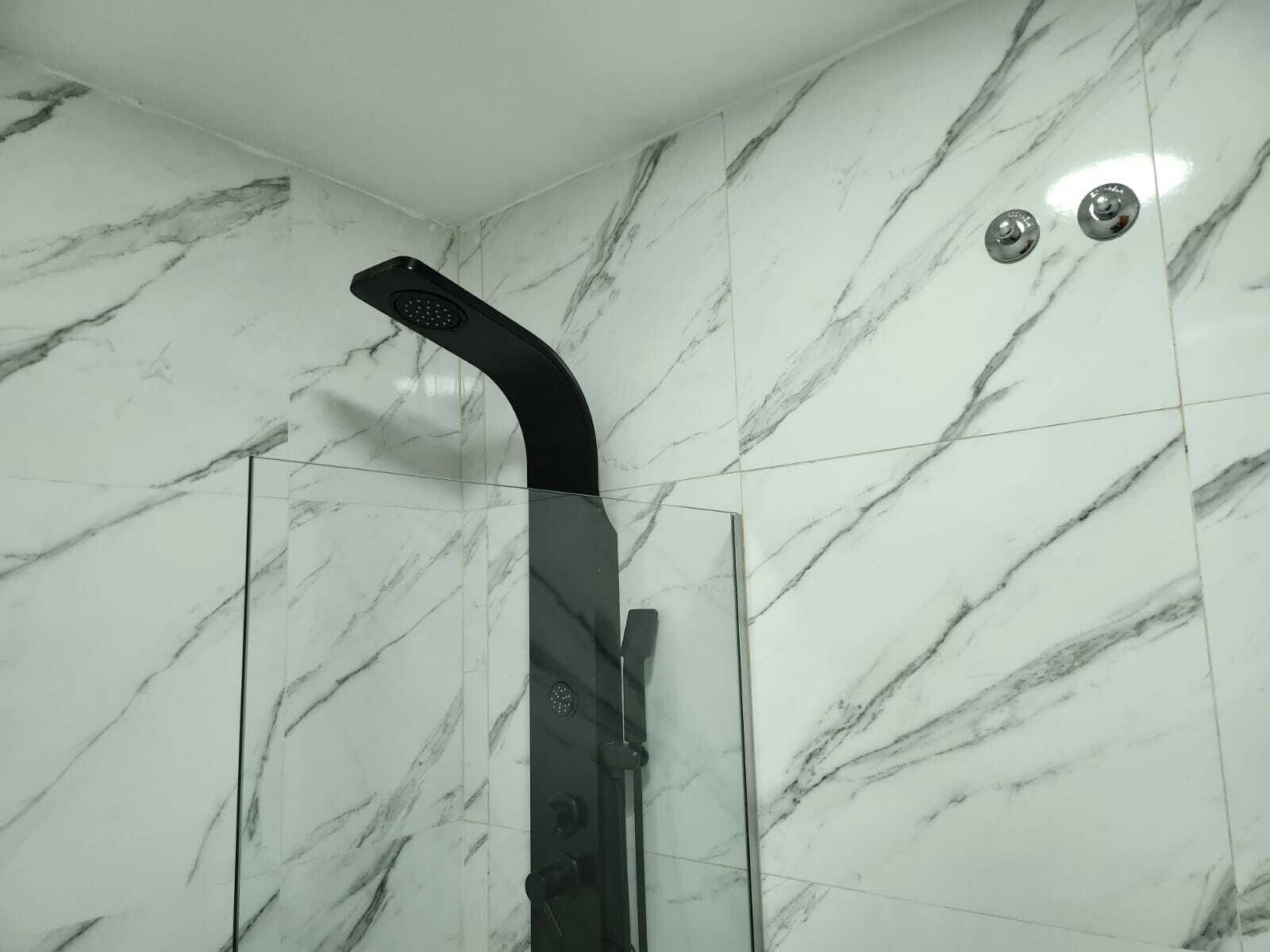 A shower with a curved head and a control panel.