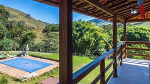 Un'area esterna riparata con piscina, terrazza in legno e vista su un paesaggio collinare.