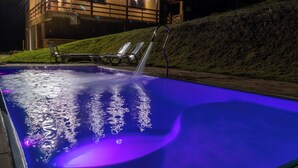 Una piscina con fontana, sedie a sdraio e un edificio sullo sfondo.