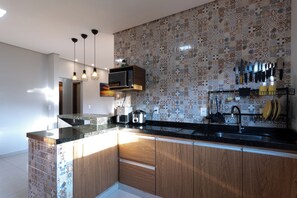 Uma cozinha moderna com painel decorativo, armários de madeira e bancada preta.