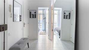 A hallway with a bench, a coat rack, and a door leading to a bedroom.