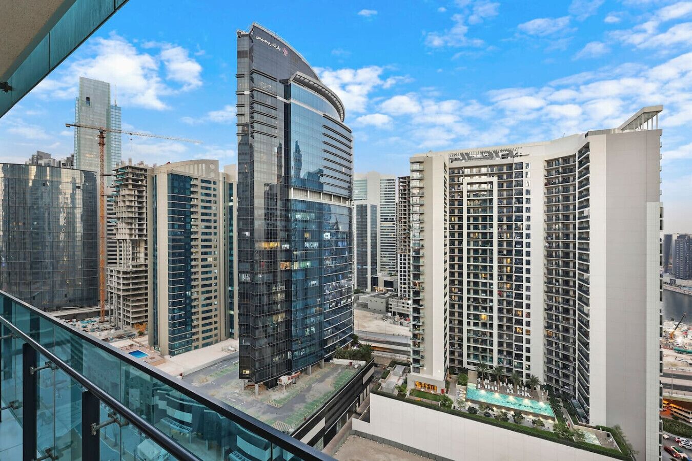 A high-rise building with a modern glass facade, surrounded by other tall buildings, and a clear blue sky.