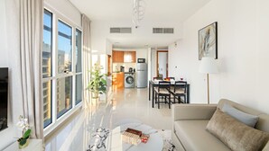 A modern apartment with a living room, dining area, and kitchen. - Stylish 1BR Retreat in Dubai | Lake Views, Pool, Gym & Prime City Location (Dubai Production City)