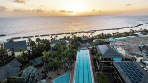 Un complex turístic amb piscina, palmeres i vistes a l'oceà al capvespre.