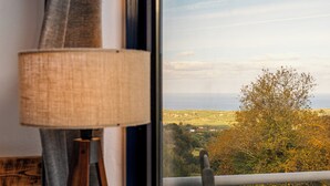 Une fenêtre donnant sur un paysage, une lampe et un objet en bois.