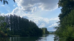 A calm river with dense trees on both sides, a clear sky, and a dirt path along the riverbank. - L'Eau Posée - Standing gîte facing the Yonne river (Villecien)
