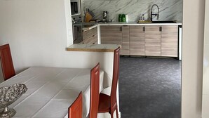 A modern kitchen with a marble backsplash, wooden cabinets, and a dining area with a table and chairs. - L'Eau Posée - Standing gîte facing the Yonne river (Villecien)