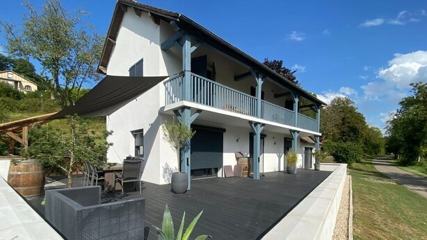 A two-story building with a balcony, outdoor seating area, and a landscaped garden. - L'Eau Posée - Standing gîte facing the Yonne river (Villecien)