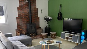 A living room with a fireplace, a television, and a guitar. - L'Eau Posée - Standing gîte facing the Yonne river (Villecien)