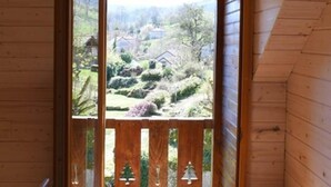 Eine Holzhütte mit einem großen Fenster und Blick auf einen angelegten Garten.