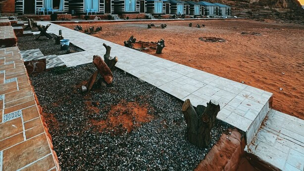 Una hilera de estructuras modernas con forma de tienda, con un sendero pavimentado que las conecta, frente a un fondo de formaciones rocosas rojas.