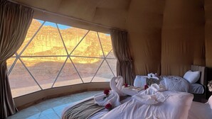 Una habitación amplia con una cama grande, vistas a un paisaje desértico a través de una ventana de diseño geométrico y una decoración de estilo moderno.