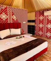 Un dormitorio amplio con una cama grande, paredes con un estampado rojo y blanco, y techo de madera.