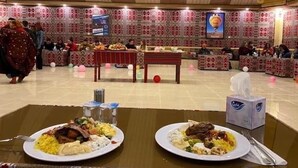 Un comedor con mesas dispuestas para comidas, una pantalla de televisión y adornos de pared con diseños.