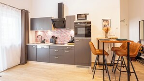 A modern kitchen with grey cabinets, a microwave, oven, and a dining area with two chairs. - Soulscape Apartment CityCenter - compact & luxurious loft apartment in the city center (Zwickau)
