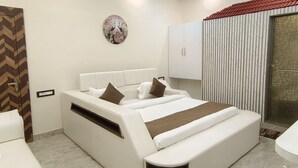 A modern bedroom with a large bed, white curtains, a decorative wall piece, and a wardrobe. - Hotel Devvanshi Vila (Varanasi)