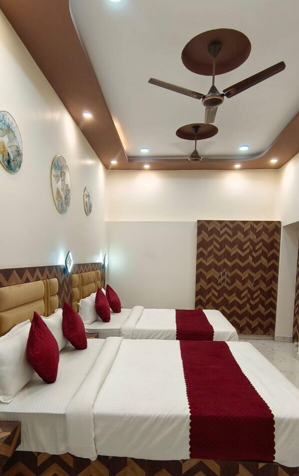 A hotel room with a bed, a ceiling fan, and a patterned wall. - Hotel Devvanshi Vila (Varanasi)