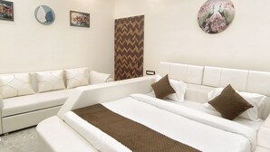 A modern hotel room with a large bed, a sofa, and a decorative wall with artwork. - Hotel Devvanshi Vila (Varanasi)