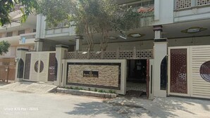 A modern residential building with a gated entrance, a stone facade, and a balcony with railings. - Hotel Devvanshi Vila (Varanasi)