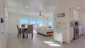 A spacious living area with a dining table, chairs, a sofa, and a kitchen with cabinets and appliances. - Ocean views, steps to beach, family, dining, shops (San Diego)