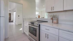 A modern kitchen with white cabinetry, stainless steel appliances, and a marble countertop. - Ocean views, steps to beach, family, dining, shops (San Diego)