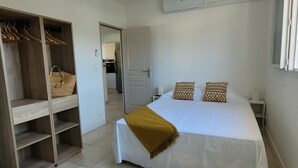 A bedroom with a bed, a wardrobe, and a door leading to a kitchen. - Villa Porto Vecchio, near beach, 8/10 pers (sainte lucie de Porto vecchio)