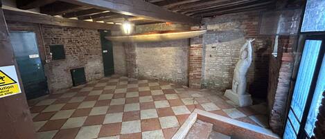 A room with a checkered floor, exposed brick walls, and a stone statue.