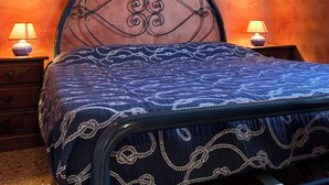 A bedroom with a bed, two bedside lamps, and exposed wooden beams on the ceiling.