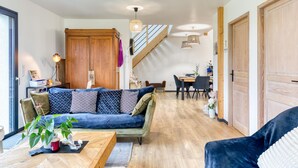 A modern living room with a blue sofa, wooden flooring, and a staircase leading to another level. - Amazing home in Venon with WiFi (Venon)