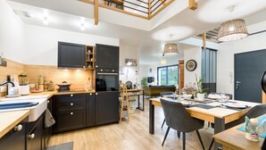 A modern kitchen with dark cabinetry, a wooden countertop, and a dining area with a table set for two. - Amazing home in Venon with WiFi (Venon)