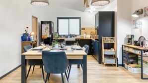 A modern kitchen with a dining area, featuring a wooden table, chairs, and pendant lights. - Amazing home in Venon with WiFi (Venon)