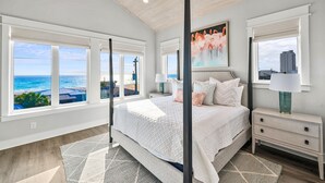 A bedroom with a large bed, a nightstand, and a view of the ocean. - Pier Park Paradise! Gulf Retreat, Private Pool, Sleeps 24 (Panama City Beach)