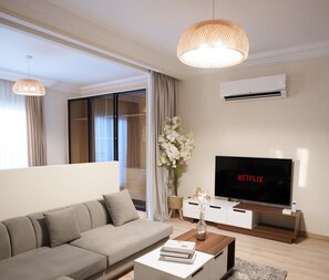Apartamento família, vista para a cidade | Área de estar | TV de tela plana