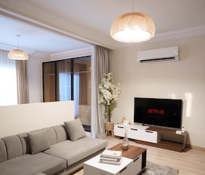 Apartamento família, vista para a cidade | Área de estar | TV de tela plana