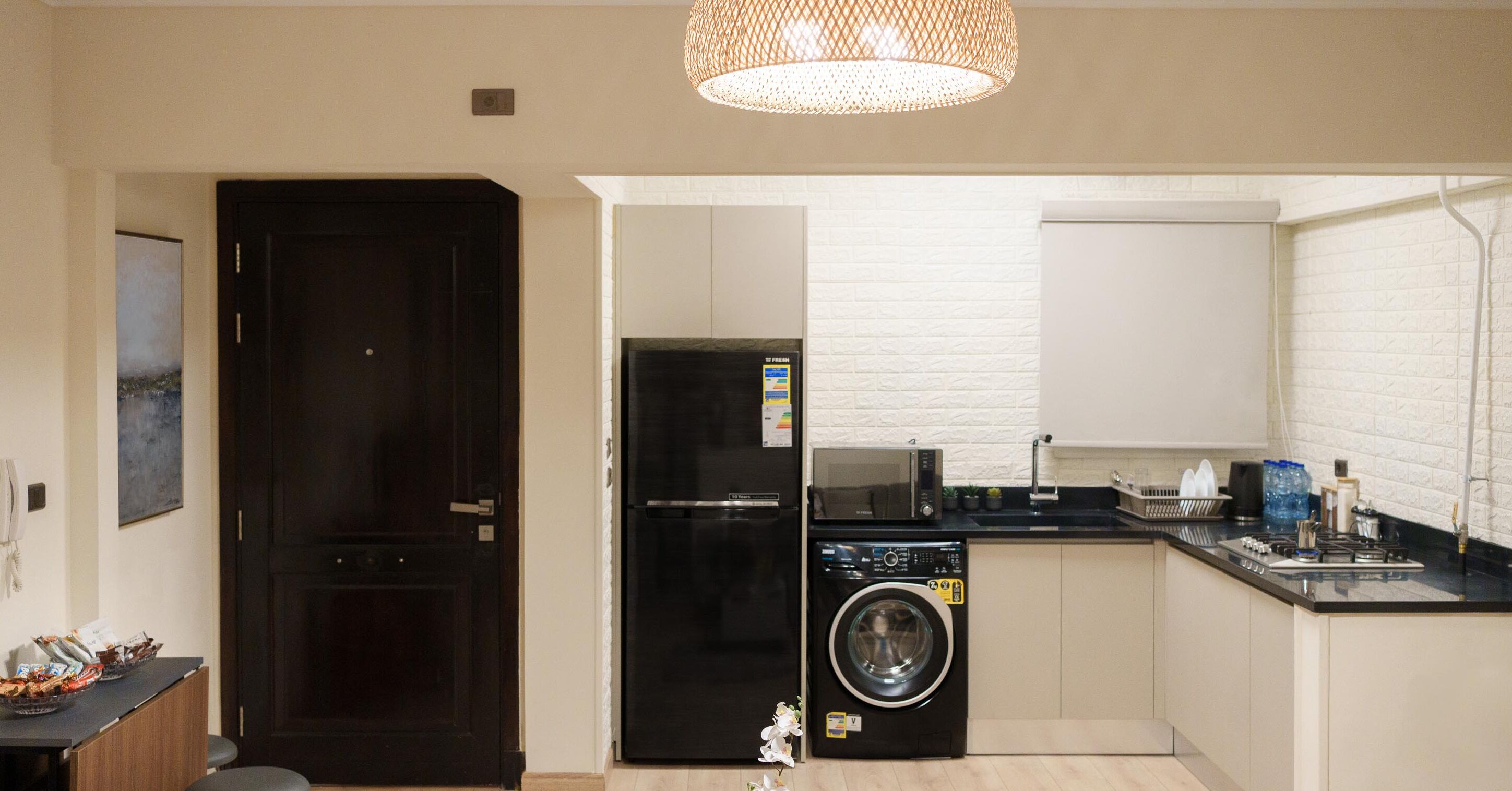 A compact kitchen with a black refrigerator, a washing machine, and a microwave.