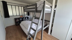 A bunk bed room with a ladder, a bookshelf, and a door.