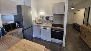 A modern kitchen with stainless steel appliances, a wooden countertop, and a tiled backsplash.