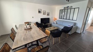 A modern living room with a dining area, a sofa, and a TV.